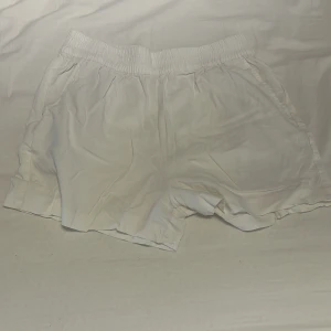 Vita linne shorts med resårmidja - Snygga vita shorts med loose passform och bred resår i midjan. De har fickor på sidorna och en bakficka, perfekta för chill dagar. Materialet känns lätt och luftigt, vilket gör dem grymma för varma sommardagar.