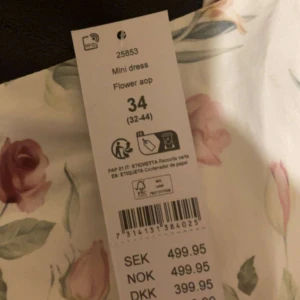 Blommig vit kortklänning - Supersöt vit kortklänning med blommigt mönster i rosa, rött och grönt. Klänningen har en utställd kjol och är ärmlös, perfekt för sommarens alla tillfällen. Materialet känns lätt och luftigt, och den har en feminin och fräsch vibe. Två stycken en på storlek 36 och en på 34