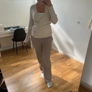 Beige omlott kofta från Esmara - Säljer en beige ribbad omlottkofta från Esmara med knyt i sidan och v-ringad hals. Koftan har långa ärmar och är gjord i mjukt stickat material som är perfekt för lager-på-lager. Enkel att styla med både jeans och mjukisbyxor. Super mysigt material, du kan själv justera hur urringad samt tajt du vill ha den.  