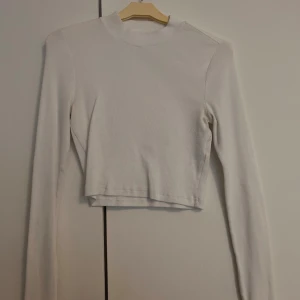 Vit och svart croppade toppar - Två croppade toppar i vitt och svart med lång ärm. Båda är ribbade och har en slim passform. Säljes endast tillsammans i paketpris.