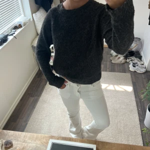 Mörkgrå stickad tröja med rund hals - Säljer en mörkgrå stickad tröja med rund hals och långa ärmar. Tröjan har en loose passform och är perfekt för kyliga dagar. Materialet är mjukt och ger en skön känsla mot huden. Enkel och stilren design som funkar till många olika outfits.