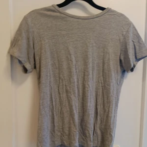 Grå basic t-shirt i bomull - En enkel grå t-shirt med rund hals och korta ärmar. T-shirten är tillverkad i mjuk bomull och har en klassisk, normal passform. Perfekt att matcha med jeans eller shorts för en chill look.