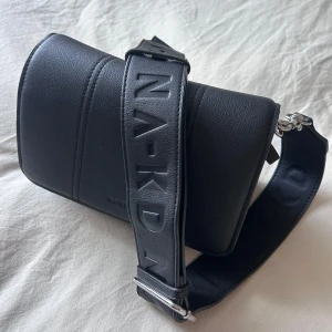 Svart väska  NA-KD - Snygg svart axelväska från NA-KD med bred axelrem. Väskan har en praktisk dragkedja inuti och en stilren design som passar till många tillfällen. Använd fåtal gånger 💕