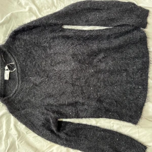 Mörkgrå fluffig tröja från Gina Tricot - Säljer en supermjuk och fluffig mörkgrå tröja från Gina Tricot. Perfekt för kyliga dagar med sin mysiga känsla. Tröjan har långa ärmar och en rund halsringning. Passar perfekt för en avslappnad stil.