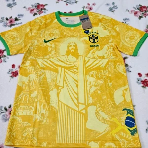 Gul Brasilien fotbollströja från Nike - Säljer en gul Brasilien fotbollströja från Nike med gröna detaljer. Tröjan har ett stort tryck av Kristusstatyn på framsidan och är kortärmad. Perfekt för fotbollsfans som vill visa sitt stöd för Brasilien! 🇧🇷