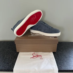 Christian Louboutin skor - Snygga grå sneakers i mocka från Christian Louboutin med den ikoniska röda sulan. Skorna har en rund tå och snörning för en klassisk look. Perfekta för dig som vill ha stil och komfort i ett. Kom priv innan köp.