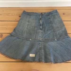 Jeanskjol från Odd Molly - Säljer en snygg jeanskjol från Odd Molly med en unik design. Kjolen har en volangdetalj och en rå kant nertill. Perfekt för en avslappnad stil.
