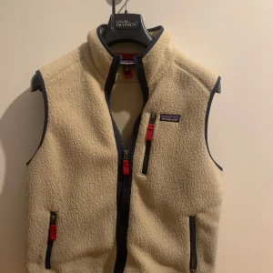 Beige fleeceväst från Patagonia - Säljer en snygg beige fleeceväst från Patagonia med dragkedja och flera praktiska fickor. Perfekt för lager-på-lager under kyliga dagar. Västen har en klassisk design med mörka detaljer vid kanterna och dragkedjorna. Storlek M / skick 8/10 priser kan diskuteras vid snabb afär 