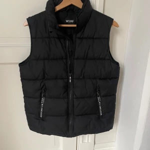 Väst - Svart dunväst från woxo Urban streetwear. Storlek 158. Bra skick och inga defekter, hål eller liknande. Bara att höra av sig vid frågor eller funderingar!