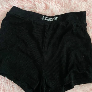 Svarta shorts med textdetalj - Snygga svarta shorts med text broderad i vitt på midjan. Perfekta för en avslappnad stil. Tillverkade i ett mjukt och bekvämt material.