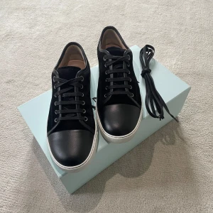 Svarta sneakers från Lanvin - Snygga svarta Lanvin med en stilren design. Box och skosnören i original ingår. Modellen heter: Lanvin DBB1 Nappa Cap Tor Sneaker Black. Köpta på Care of Carl 2024-07-16. Hör av er vid funderingar👍