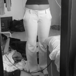 Vita kostymbyxor - Snygga vita kostymbyxor med låg midja och bootcut-stil. Perfekta för en stilren look. är lite åt det beiga hållet och lite smutsiga längst ner vid slitsen annars fint skick
