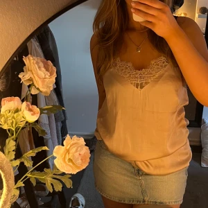 Rosa linne från H&M - Säljer ett superfint satin linne i en rosa från H&M med en vacker spetsdetalj vid halsringningen. Super snyggt och säljs inte längre (det är en gammal modell) 🩷🩷Passar M/S storleksmässigt 