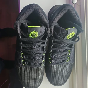 Svarta Nike LBJ Witness VII sneakers - Snygga svarta Nike LBJ Witness VII sneakers med neongröna detaljer. Skorna har en quiltad ovandel och snörning. Perfekta för basket eller vardagsbruk med en slitstark sula och bekväm passform.