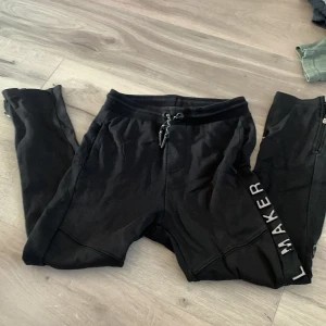 Svarta mjukisbyxor från Zara - Säljer ett par svarta mjukisbyxor från Zara med snörning i midjan och textdetalj längs benet. Perfekta för en avslappnad stil. * Barnsize 