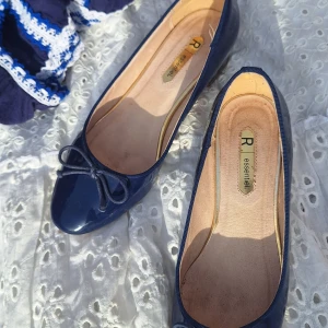 Mörkblå ballerinaskor med rosett - Snygga mörkblå ballerinaskor från R essentiel. De har en rosett på ovansidan och låg klack. Köpta på vinted men är i fint skick🫶 säljer då de inte passade mig😭