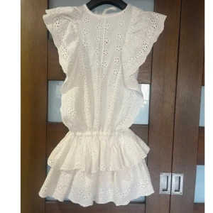  Studentklänning med volanger - Vit studentklänning med broderade blommor och volangdetaljer. Den har korta ärmar och en söt knytning i nacken. Perfekt till studenten eller sommaren❤️aldrig använd så i nyskick. Pris kan diskuteras ❤️