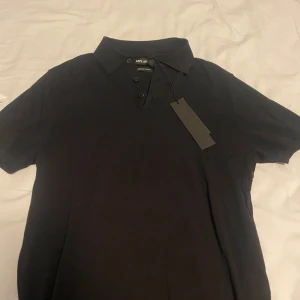 Svart pikétröja från Replay - Snygg svart pikétröja från Replay i premium bomull. Tröjan har en klassisk krage med knappar och korta ärmar. Perfekt för en stilren look.