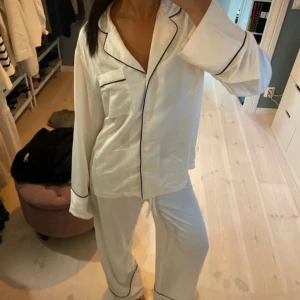 Vit pyjamas med svarta detaljer - Säljer en supermysig vit pyjamas med svarta kantdetaljer. !inte mina bilder!