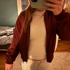 Vinröd bomberjacka - Säljer en snygg vinröd bomberjacka med dragkedja framtill. Jackan har en normal passform och långa ärmar. Perfekt för höst och vår! Storleken är L men skulle säga att den är dom small!😇😇