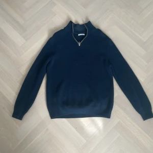 Mörkblå tröja med dragkedja från Zara - Säljer en stilren mörkblå tröja från Zara med dragkedja vid halsen. Perfekt för kyligare dagar och passar bra till både jeans och chinos. Tröjan har långa ärmar och en klassisk passform.