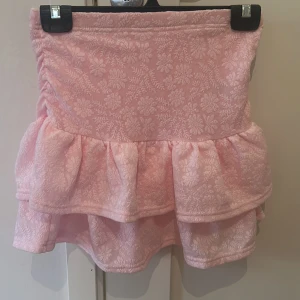 Rosa blommig kjol med volang från SHEIN - Söt rosa kjol med blommigt mönster och volangdetaljer. Perfekt för en somrig look. Kjolen har en tight passform upptill och volanger som ger en lekfull känsla. Kjolen har inbyggda shorts i.