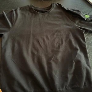 Svart sweatshirt från Stone Island - Säljer en stilren svart sweatshirt från Stone Island med deras ikoniska logga på ärmen. Tröjan har en klassisk rund halsringning och långa ärmar. Perfekt för en casual look.