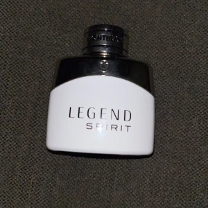 Legend Spirit Parfym FULL! - Säljer en stilren och elegant parfymflaska från Montblanc, Legend Spirit. Flaskan är vit med en svart topp och har en avtagbar kork med Montblancs ikoniska stjärnlogo. Perfekt för den som söker en fräsch och maskulin doft.