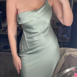 Ljusgrön klänning - Snygg ljusgrön klänning i satin med one-shoulder och en omlott-detalj. Perfekt för speciella tillfällen som bal, bröllop eller annat. Maxiklänning men liite kort på mig som är 173 lång.