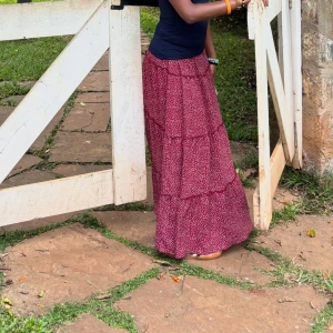 Röd långkjol med småmönster - Säljer en röd långkjol med småmönster. Kjolen har en volangdetalj som ger den ett extra lyft. Perfekt för en avslappnad dag ute eller en somrig kväll.