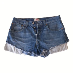Blå jeansshorts från Levi's - Säljer ett par klassiska blå jeansshorts från Levi's 501 med knappgylf och fransiga kanter. 