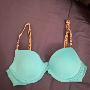 Turkos och leopardmönstrad BH från Victoria's Secret PINK - Säljer en snygg turkos BH från Victoria's Secret PINK med leopardmönstrade axelband. Insidan är rosa vilket ger en cool kontrast. Perfekt för dig som vill ha något unikt och bekvämt. 🐆💙