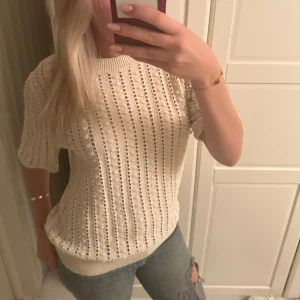 Vit stickad tröja - Säljer en stilren vit stickad tröja med korta ärmar. Tröjan har ett luftigt mönster och ribbade kanter. Perfekt för en avslappnad look. Hör av dig vid intresse!