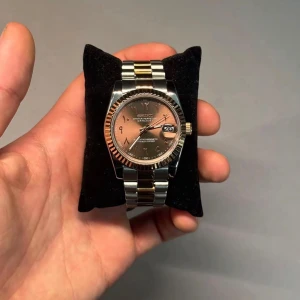 🍫arabic dial🍫 - Elegant klocka med tvåfärgad länk i silver och guld. Urtavlan är brun med datumvisning och tydliga markeringar. Perfekt för en stilren look.