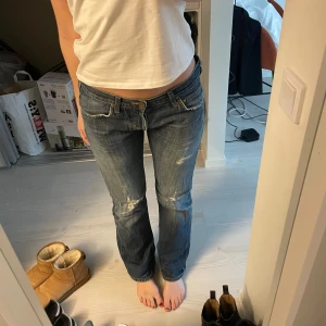 Blå jeans med slitningar - Snygga blå jeans från Lee med slitningar på låren och knäna. De har en låg midja och en bootcut-stil. Jag är 170cm! 