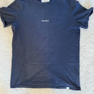 Mörkblå t-shirt från Les Deux - Säljer en stilren mörkblå t-shirt från Les Deux med rund hals och korta ärmar. Perfekt för en avslappnad look. Tillverkad i Portugal. Storlek M. Mycket bra skick