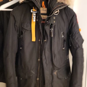 Svart jacka från Parajumpers - Säljer en svart jacka från Parajumpers med pälsdetaljer på huvan och flera praktiska fickor. 