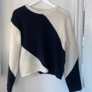 Mörkblå och vit stickad tröja - Säljer en snygg mörkblå och vit stickad tröja med ett diagonalt mönster. Tröjan har en rund hals och långa ärmar, perfekt för kyligare dagar. Den är både stilren och bekväm, ett måste i garderoben!  Ej använd och hyfsad ny!