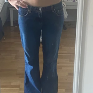 Blå bootcut jeans från Calvin Klein - Snygga blå bootcut jeans från Calvin Klein med klassisk femficksdesign och märkets logga på bakfickan. Jeansen har en låg midja och är tillverkade i ett slitstarkt denimtyg. Perfekta för en avslappnad stil.