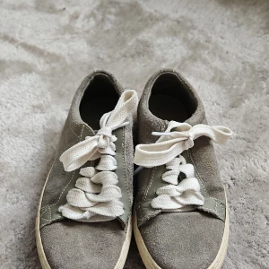 Grå sneakers från Zweigut - Snygga grå sneakers från Zweigut i mocka med vita snören. Skorna har en rund tå och en klassisk design som passar perfekt till vardags. De har en ljus sula som ger en fräsch look.