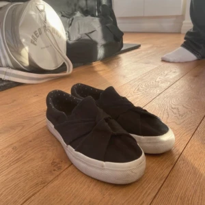 Svarta sneakers med knytning från Anna Field  - Snygga svarta sneakers med en unik knytning över ovandelen. Använt fåtal gg