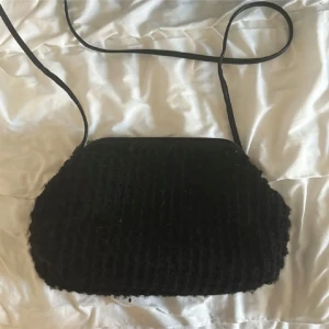 Svart axelväska med quiltad design - Snygg svart axelväska med quiltad design och justerbar axelrem. Väskan har en rymlig insida med ljus foder och innerficka. Perfekt för att bära dina dagliga nödvändigheter då du får plats med allt du behöver.