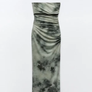 Grön mönstrad klänning - Snygg grön klänning med unikt mönster och draperad design. Klänningen har en smickrande passform och är perfekt för en stilfull look. Den är axelbandslös och har en lång längd som ger en elegant siluett.