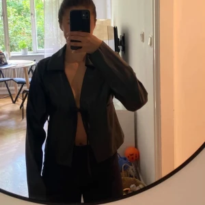 Svart kort blazer - Svart kort blazer från Chiquelle med knytning framtill. Helt ny med prislapp kvar. 