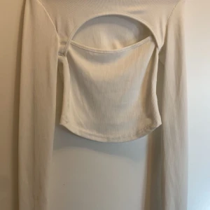 Vit ribbad långärmad topp - Säljer en stilren vit ribbad topp med lång ärm och en unik öppen ryggdesign. Perfekt för att ge en trendig touch till din outfit. Passar bra till både jeans och kjol. Den är i nyskick från Shein i storlek XS
