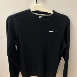 Svart långärmad tröja från Nike - Säljer en stilren svart långärmad tröja från Nike. Perfekt för en avslappnad look eller träning. Tröjan har en normal passform och är tillverkad i ett mjukt material. Jätte bra skick.