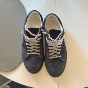 Mörkblå sneakers med snörning - Snygga mörkblå sneakers i mocka med vita snören. Perfekta för en avslappnad stil. Skorna har en klassisk design med rund tå och en bekväm sula. Dom är i storlek 42 men passar utmärkt till 42/5 pris går att diskutera