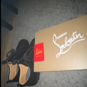 Svarta skor från Christian Louboutin - Säljer ett par eleganta svarta skor från Christian Louboutin med den ikoniska röda sulan. Skorna har snörning och är perfekta för en stilren look.