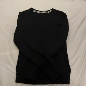 Svart långärmad tröja från Pier One - Snygg svart långärmad tröja från Pier One med en stilren design. Perfekt för en minimalistisk look. Tröjan har en diskret randig detalj vid halsen som ger en extra touch.