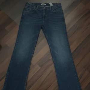 Blå jeans från Pull&Bear - Snygga blå jeans från Pull&Bear med klassisk femficksdesign och knappgylf. De har en rak passform och är perfekta för en avslappnad stil. Jeansen har en mörk tvätt som ger en snygg look.